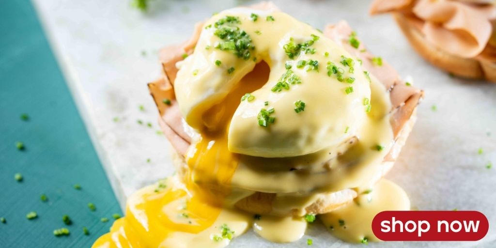 Yo-Egg vegan Benedict with plant-based poached eggs, hollandaise sauce, and chives on a toasted English muffin.